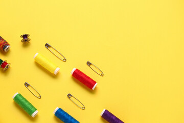 Thread spools and pins on yellow background