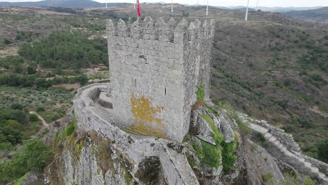 Sortelha medieval castle or Castelo de Sortelha with portuguese flag on top. Aerial drone circling
