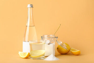Bottle and glass of water with lemon on color background