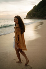 Happy young woman walk at seashore during sunset. Summertime, vacation by the sea