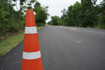Red rubber cones are placed in the paved road.