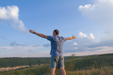 Fototapeta premium The man raised his hands to the side and enjoys the view of nature