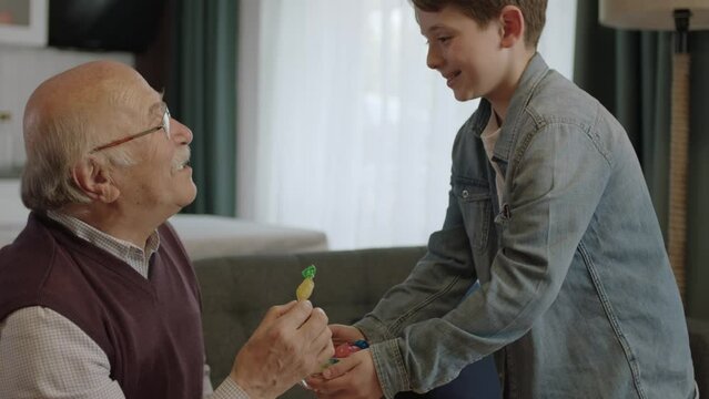 Boy offering candy in bowl to his old grandfather.Little boy offering candy to his elderly grandfather to celebrate the traditional Eid al-Fitr (candy feast) after the end of Ramadan.
