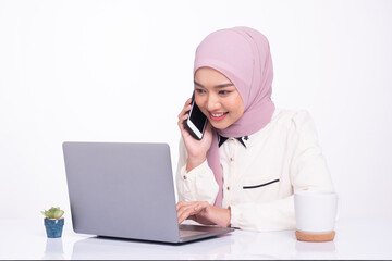 Female Muslim in hijab working on laptop in office room. Woman fully absorbed in work.
