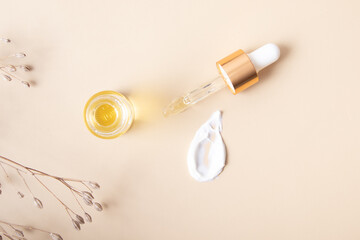 Cosmetic bottle with pipette and smear of cream on a beige background