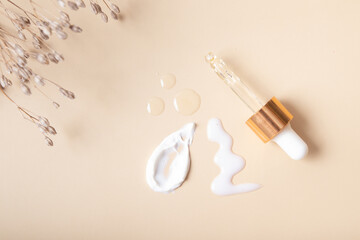 Pipette and cosmetic smears with cream and drops of oil or serum on a beige background top view