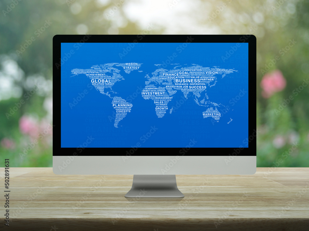 Poster global business words world map on desktop modern computer monitor screen on wooden table over blur 