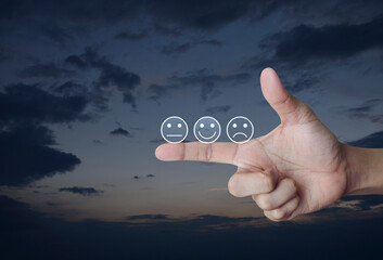 Excellent smiley face rating icon on finger over sunset sky, Business customer service evaluation and feedback rating concept