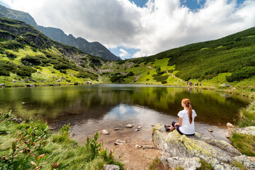 Girl sitting and looking on beautiful nature with lake and mountains in Western Tatras in Slovakia
