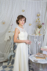Fototapeta na wymiar A girl in a white long elegant dress in a pastel-light interior in the Provence style.