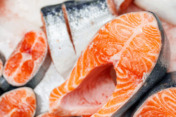 Trout, cut into pieces, laid out on ice on store counter. Pieces of red fish in close-up.