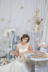 A girl in a white long elegant dress in a pastel-light interior in the Provence style.