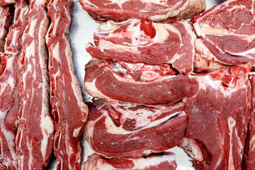 Top view of pieces of fresh beef with fat lying on counter at village market.