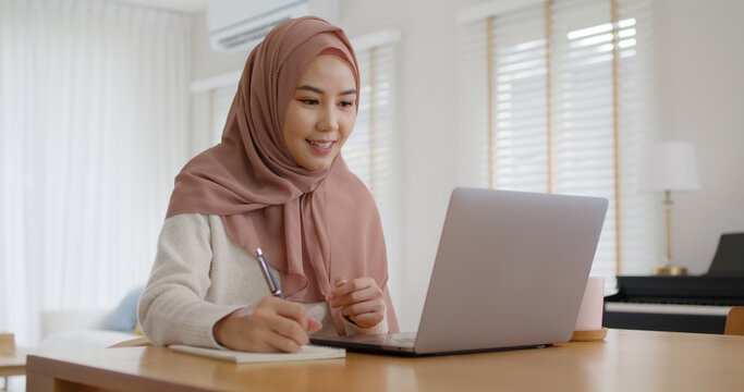 Asia arab people young woman wear hijab headscarf plan study MBA college class note idea data in sale report remote work at home on laptop. Happy advisor lifestyle smile cowork smart workforce job.