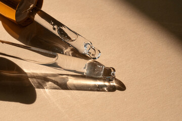 Two pipettes of cosmetic gel on a beige background.