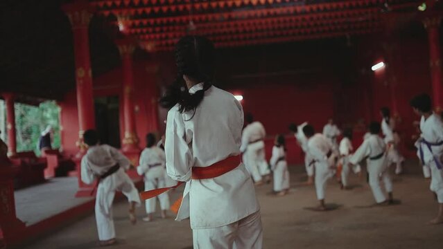 Traditional karate class, big group of children learning japanese martial arts on a temple.