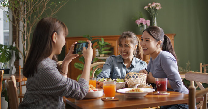 Small girl group party asia people busy talk smile eat brunch food drink. Young woman fun happy hour meal shoot photo of dish plate salad bowl on table post ig reel story app in vegan cafe bar shop. - Powered by Adobe