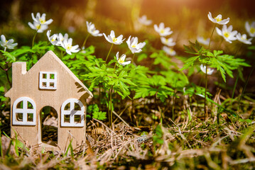 The symbol of a house in a forest clearing among white snowdrops