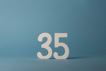 White wooden number thirty-five 35 on blue background.
