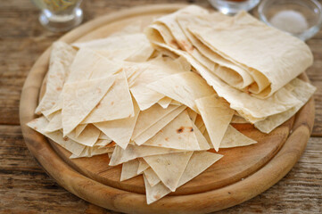 Thin pita (lavash) cut into pieces on a wooden board.