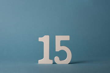 White wooden number fifteen 15 on blue background.