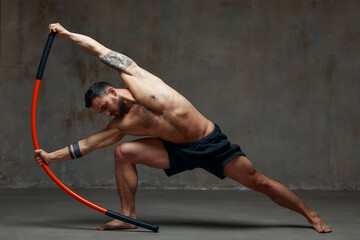 A ninja man holds on to a fighting stick and attacks close-up on gray studio background