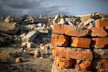 Fototapeta premium Red bricks on the background of a destroyed building and blue sky