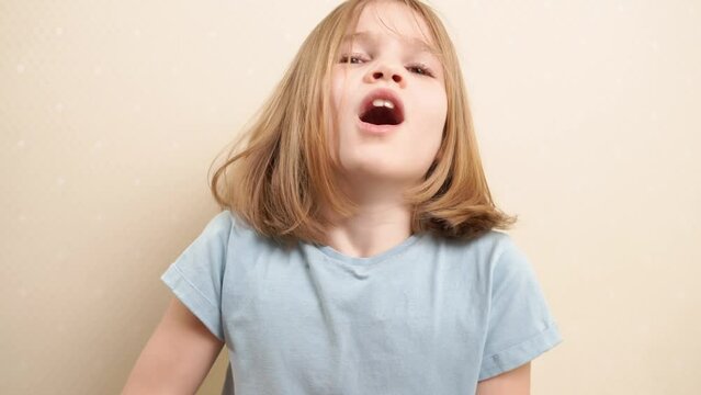 yawning cute little girl with blonde hair in a blue T-shirt. daily routine for children. early rises to schools. fatigue.