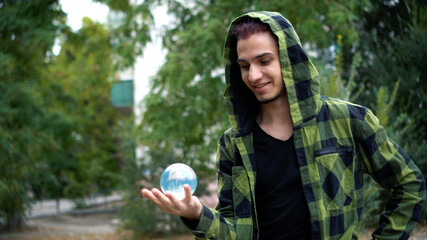 Guy shows trick with transparent glass sphere. Artist is engaged in juggling.