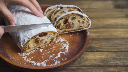 Slicing bread on plate, soft focus. Wooden table with delicious dessert.