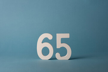 White wooden number sixty-five 65 on blue background. - obrazy, fototapety, plakaty