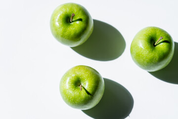 flat lay with green apples with shadows on white.