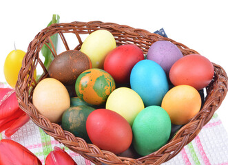 Close up of colorful Easter eggs in a basket and colorful tulip decorations on an isolated white background