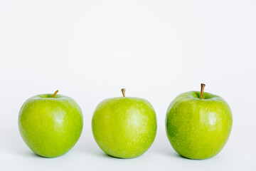 row of green and ripe apples on white.