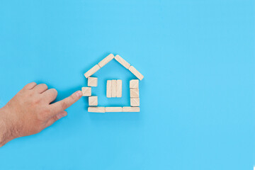 Fototapeta na wymiar Small house made of wooden blocks on a blue background