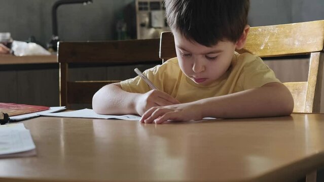 Close up image of focused schoolboy hands holding pencil writing and doing home work on class book. Hand drawing. Writing education concept. Child development.