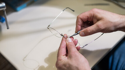 Installation of nose pads in glasses. A male technician repairs broken glasses