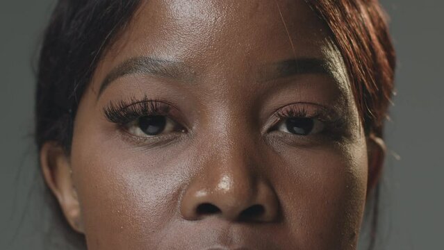 Closeup brown eyes with long lashes of pensive black female. African american woman blinking looking at camera. ProRes