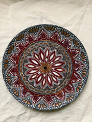 Decorative ceramic plate with  different colors. painted plate on white background, closeup, top view. Decorative porcelain plate painted with acrylic paints, dot painting
