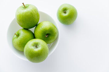 top view of ripe apples in bowl on white.