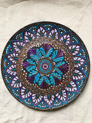 Decorative ceramic plate with  different colors. painted plate on white background, closeup, top view. Decorative porcelain plate painted with acrylic paints, dot painting