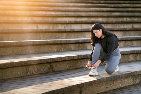 Young Brunette Woman Tying Her Shoes Getting Ready To Play Exercise