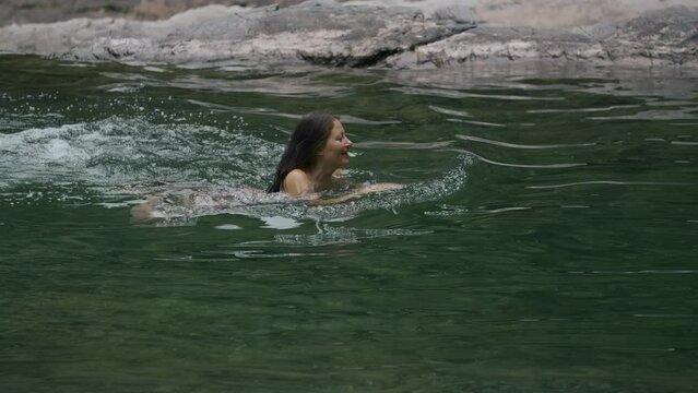 Woman swimming in the green lake or river. Creative. Concept of summer vacation, swimming in cold summer stream.
