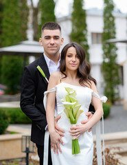 Naklejka premium Beautiful young newlyweds couple embracing on the background of a beautiful building. High quality photo