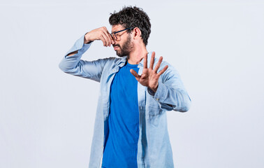 Confused unhappy man grabbing nose with fingers and stretching hand out feeling disgusted, A man...