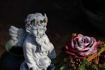 Weißer Engel mit Rosenkranz auf dem Kopf und roter Rose auf schwarzem Hintergrund - obrazy, fototapety, plakaty