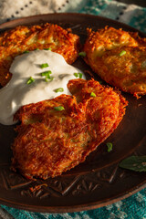 Fried potato pancakes on a clay brown plate, sour cream, green onions. food, potato pancakes, dish