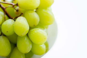 close up view of fresh green grapes in bowl on white.