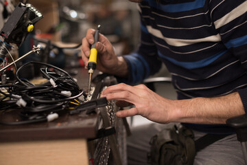 Industrial worker man soldering cables of manufacturing equipment in a factory. Selective focus