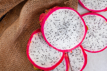 Dragon fruit slices on grey mottled surface and ample copy space